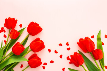 Fresh red tulips and hearts on pink background, concept of spring and holidays or Valentine's Day, top view, copy space