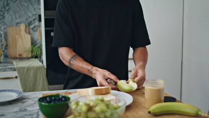 Man hands peel fruit at home kitchen closeup. Unknown guy preparing breakfast
