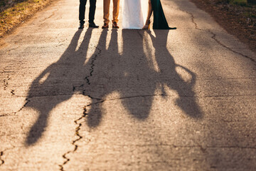 Shadow silhouette at sunset. Newlyweds and maid of honor and best man. Friends forever concept on a...