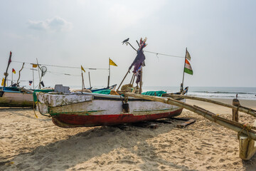 Fototapeta na wymiar old fishing boats in sand on ocean in India on blue sky background