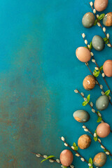Cosmic Easter eggs with willow branches on a turquoise background, top view, copy space