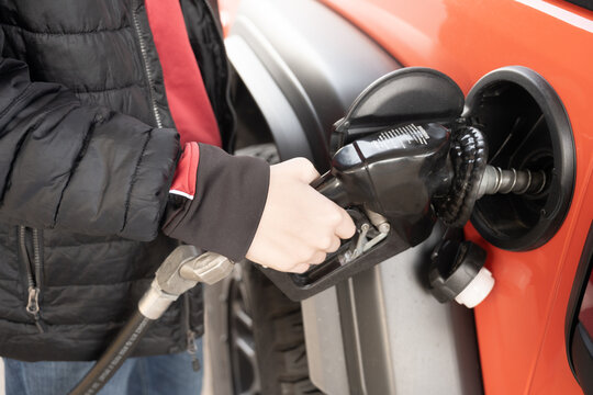 A Person Putting Fuel In Their Vehicle At The Gas Pump. 