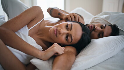 Relaxed man stroking woman hair at bed close up. Intimate couple laying together - obrazy, fototapety, plakaty