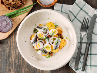 Anchovy or sprat or sardine with potatoes in restaurant-style plating, served onion and greenery....