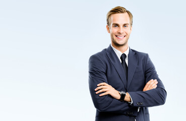 Portrait photo - happy smiling confident businessman in dark suit, necktie, standing crossed arm...