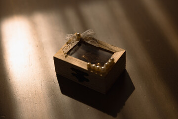 Wooden wedding rings box on a table with golden light coming through the windows. Bride and groom...