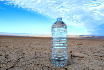 Mineral water on Drought land. Global drought. Plastic bottle with water on Dry cracked earth. Water crisis and World Climate change. Dried earth in Water crisis in nature. No freshwater in ocean.