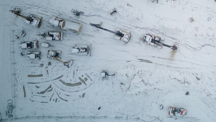 Aerial view on construction site, winter in the morning, construction machines and foundations of a new building, concept for work in difficult conditions, recession, construction. 