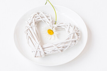 A white heart, chamomile flower  on a white plate. Table décor, Love, Valentine ’s Day Concept , Scandinavian decor, copy space