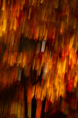 abstract blur background of fall or autumn colors in motion movement falling effect created by slow shutter speed and intentional camera movement fall leaves on trees in motion vertical fall backdrop 