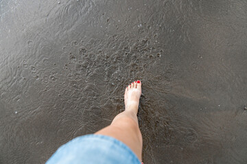 Women feet splashing and walking on the beach with red nail polish 