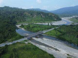Bridge over calm water with trees and plants around.