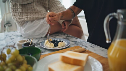 Closeup hands eating breakfast in kitchen together. Man fingers trying banana