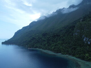 Tranquil Scene of Serene Coastal Landscape with Greenery and Mountains Reflected in the Tranquil Water in sawai saleman, maluku, indonesia