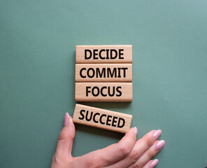 Decide Commit Focus Succeed symbol. Concept words Decide Commit Focus Succeed on wooden blocks. Businessman hand. Beautiful grey green background. Business concept. Copy space.