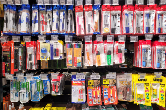 PENANG, MALAYSIA - 1 DEC 2023: 
A shelf in the grocery store is stocked with various stationery items such as correction pens, glue, tape, erasers, paper tags, and colored pencils.