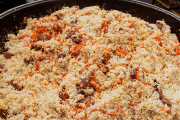 In street food festival, Uzbek pilaf is being prepared in cauldron