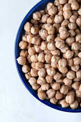 Dried chickpeas in blue ceramic bowl on white background