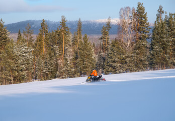 Athlete on a snowmobile moving in the winter forest in the mountains of the Southern Urals