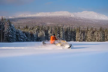 Fotobehang Athlete on a snowmobile moving in the winter forest in the mountains of the Southern Urals © 02irina