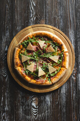 Italian pizza with meat and cheese, delicious pizza close-up on a dark background.