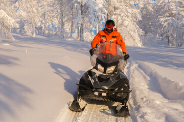 Athlete on a snowmobile moving in the winter forest in the mountains of the Southern Urals