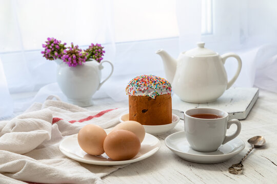 Easter still life with painted eggs, Easter cake and tea in a cup on the windowsill on a sunny day