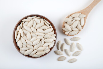 A bowl full of pumpkin seeds on white background,top view