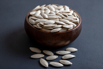 A bowl full of pumpkin seeds on black background,top view