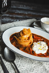 Appetizing pasta with tomato sauce and cheese on a dark wooden table. Restaurant food service.