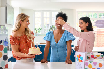 Fototapeta premium Three Mature Women Meeting At Home To Celebrate Friend's Birthday With Surprise Cake Together