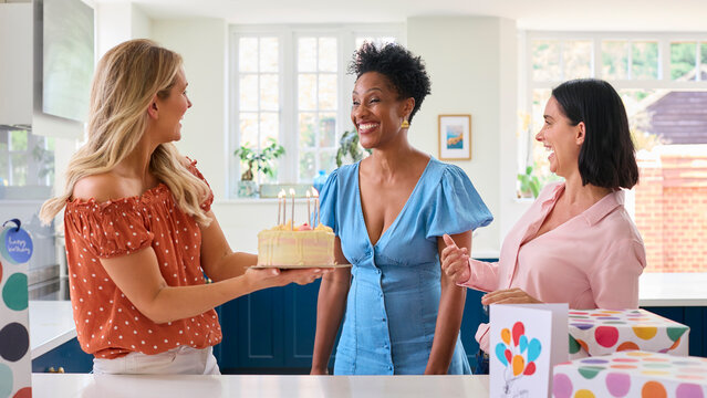 Three Mature Women Meeting At Home To Celebrate Friend's Birthday With Surprise Cake Together