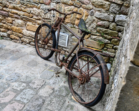 Old rusty antique bicycle along the brick wall in the village alleyway 
