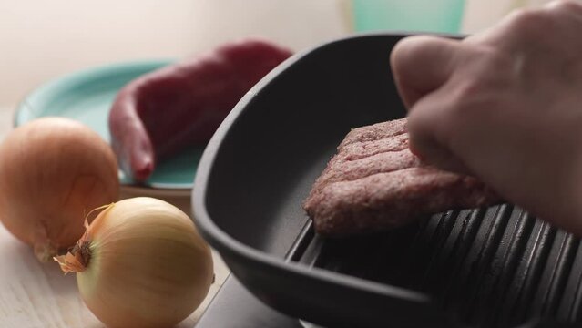 Putting Chevapchichi Sausages in Pan. Close-up, shallow dof.