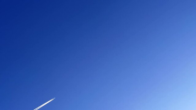 Jet contrail crossing the clear blue sky. Cloudscape.