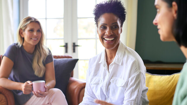 Three Mature Female Friends In Lounge At Home Meeting For A Chat And Hot Drink