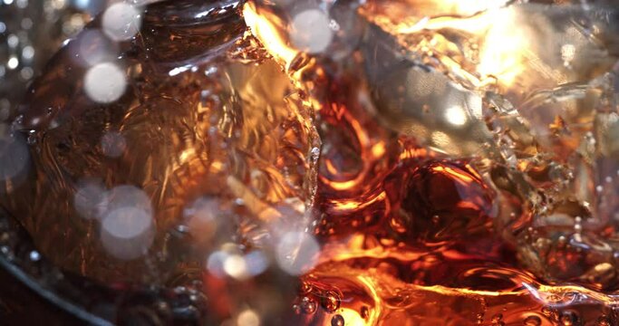 Super slow motion macro of ice cubes are falling in old malt bourbon whiskey cocktail in transparent glass is being mixed by bartender in bar or club.