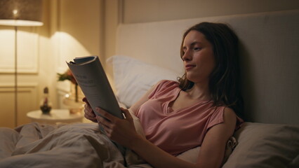 Chill girl reading book in bed closeup. Relaxed woman enjoy novel before sleep