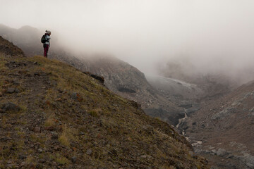 Woman on mountain meadow hiking in Caucasus mountains alone during summer foggy day
