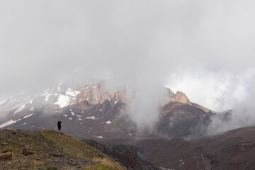 Silhouette of mountain climber in Georgia Caucasus mountains against foggy landscape of mount Kazbek