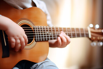 Fototapeta na wymiar Close up of a child playing guitar. A boy is playing an acoustic guitar. Training in children's mental development. Childhood dreams. Soft focus. Blurry background.