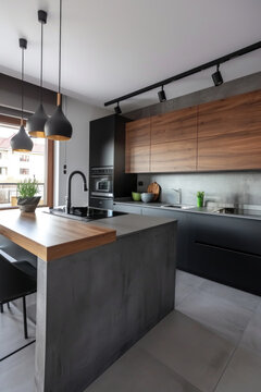 cuisine am&eacute;nag&eacute;e moderne compos&eacute;e de bois naturel et b&eacute;ton avec des &eacute;clairage suspendu de type spot