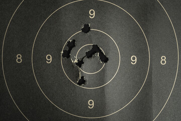Naklejka premium Paper target with bullet holes in the center, close-up photo.