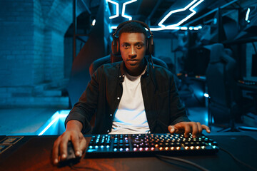 Gamer engrossed in play at a backlit keyboard setup. Concentrated player in a dim gaming...