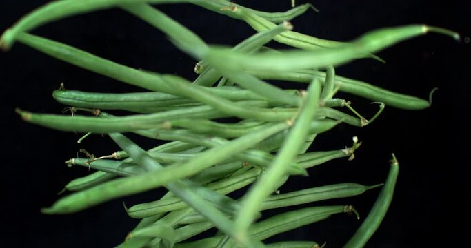Super slow motion macro of fresh ripe organic green beans are flying isolated on black background at 1000 fps.