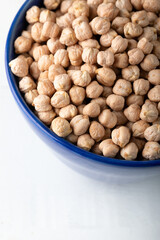 Dried chickpeas in blue ceramic bowl on white background