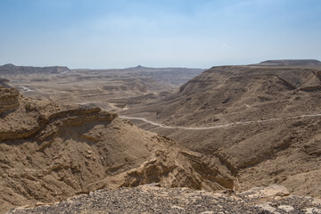 Fototapeta na wymiar Antique road in Negev Desert in southern Israel during the summer. Desert landscape with volcanic rocks nature