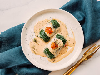 Stuffed green cabbage rolls with sauce in restaurant-style plating, served red caviar