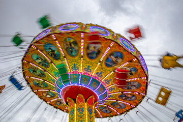 Um brinquedo gigante de rotação no parque de diversões com poucas pessoas, em um dia nublado....