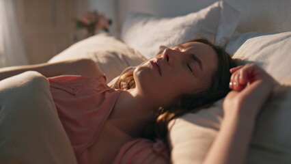 Girl sleeping morning sunlight closeup. Peaceful young woman waking up in cozy